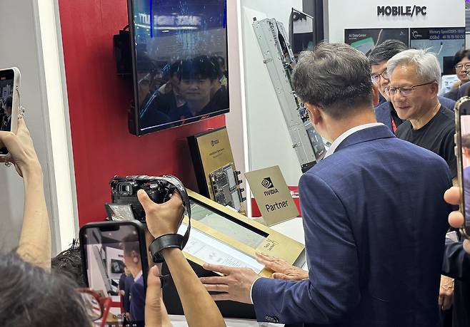 젠슨 황 엔비디아 CEO가 지난 20일 대만 타이베이 난강 전시관에서 열린 ‘컴퓨텍스 2025’에서 SK하이닉스 부스를 찾아 관계자의 설명을 듣고 있다. [연합]