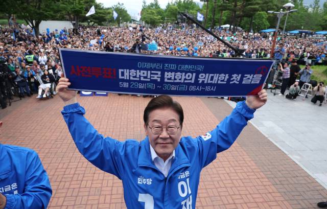 더불어민주당 이재명 대선후보가 6·3 대선 사전 투표를 일주일 앞둔 22일 경남 양산워터파크공원에서 열린 집중 유세에서 ‘사전 투표! 대한민국 변화의 위대한 첫걸음’이라고 적힌 현수막을 들어 보이고 있다. 연합뉴스