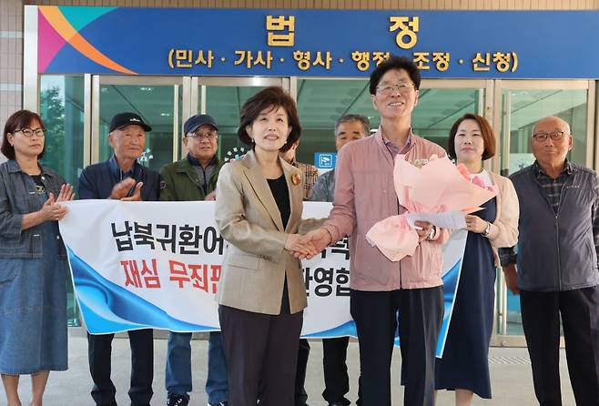 22일 오후 강원도 강릉시 춘천지방법원 강릉지원에서 열린 납북 귀환 어부 재심 선고 공판이 끝난 뒤 무죄 판결을 받은 협동호 선원 장모씨와 박선영 진실화해위원장(왼쪽)에게 꽃다발을 건네받았다./진실화해위원회