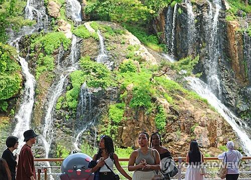 전국 대부분 낮 기온이 25도 이상을 기록하는 등 초여름 날씨를 보인 20일 서울 서대문구 홍제폭포를 찾은 시민과 관광객들이 그늘에서 폭포 풍경을 즐기고 있다. [연합뉴스]