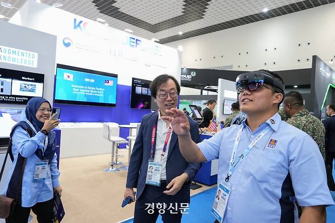 지난 21일(현지시간) 말레이시아 방산전시회 ‘LIMA 2025’에 마련된 한국관에서 조근식 주식회사 증강지능 대표(가운데)가 인공지능(AI) 기반 혼합현실(MR)을 이용한 항공 정비 시뮬레이터 체험을 안내하고 있다. 한국방위산업진흥회 제공