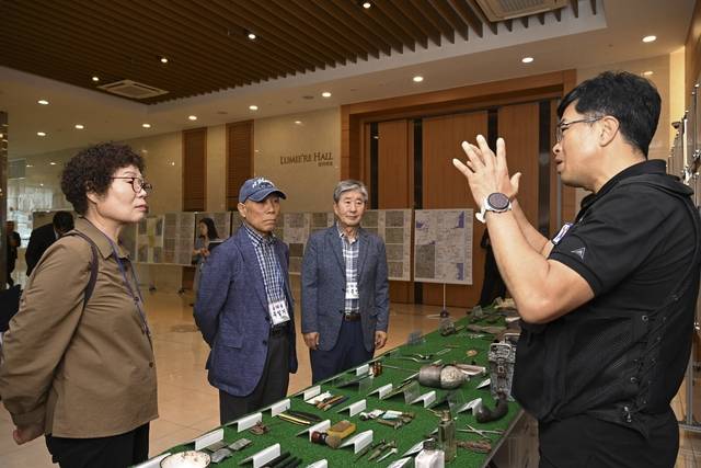 국방부유해발굴감식단 함성제(오른쪽) 상사가 22일 유해발굴사업 설명회가 진행된 대구광역시 수성구 호텔 라온제나에서 행사에 참석한  유가족에게 발굴된 사진 및 유품에 대해 설명하고 있다. 국방부유해발굴감식단 제공