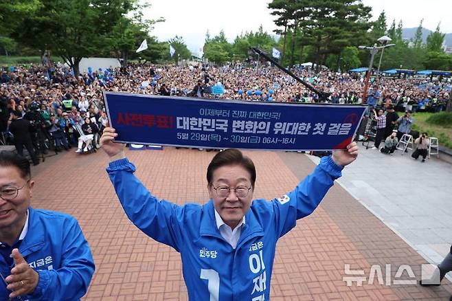 [양산=뉴시스] 조성우 기자 = 이재명 더불어민주당 대선후보가 22일 경남 양산시 양산워터파크공원에서 열린 집중유세에서 사전투표 독려 현수막을 전달 받은 뒤 들어보이고 있다. 2025.05.22. xconfind@newsis.com