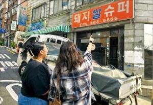 지난 21일 영화 ‘기생충’ 촬영지로 알려진 서울 아현동 돼지쌀슈퍼를 찾은 외국인 관광객들이 철거 현장을 지켜보고 있다.  /권용훈 기자