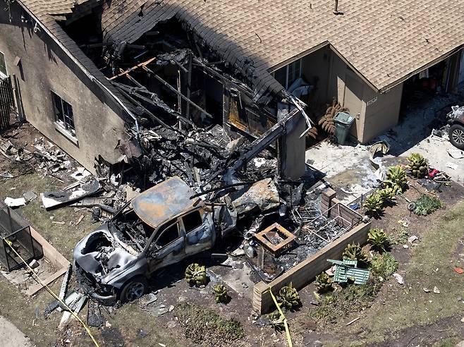 22일(현지시간) 소형 비행기가 미국 캘리포니아주 샌디에이고 주택가에 추락하면서 불에 탄 집과 자동차 잔해가 남아있다. AP연합뉴스