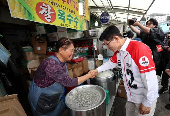 People Power Party presidential candidate Kim Moon-soo shakes hands with a merchant at a traditional market in Suwon, Gyeonggi, on May 16. [JOINT PRESS CORPS]