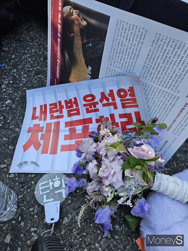 유지은씨는 국회에서 탄핵안 처리가 있던 지난해 12월14일 친구의 결혼식에 들러 부케를 받고 곧바로 집회에 참여해 한 손에는 부케를, 한 손에는 집회도구를 든채 시위를 벌였다. / 사진=유지은씨