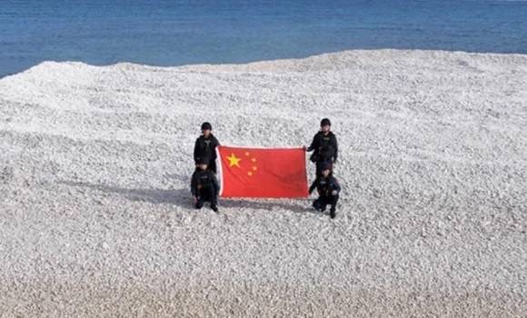 중국 해경 대원 4명이 샌디 케이에서 오성홍기를 든 모습. CCTV