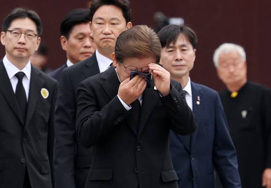 노무현 전 대통령 서거 16주기인 23일 노 전 대통령 묘역 참배를 위해 경남 봉하마을을 찾은 이재명 더불어민주당 대선후보(가운데)가 헌화를 마친 뒤 눈물을 훔치고 있다. [연합뉴스]