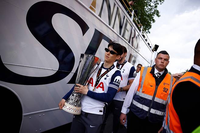 Tottenham Hotspur's Son Heung-min carries the Europa League trophy as he boards the bus for the victory parade on May 23. [AFP/YONHAP]