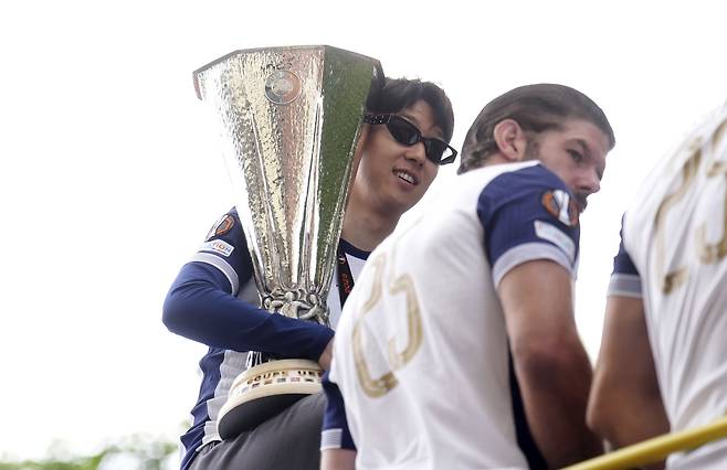 Tottenham Hotspur's Son Heung-min holds the Europa League trophy on the open-top team bus parade in North London on May 23. [AP/YONHAP]