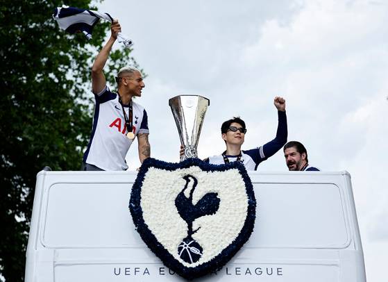 Tottenham Hotspur's Son Heung-min, center, holds the Europa League trophy as he stands with Tottenham Hotspur's Richarlison during an open-top bus parade on May 23. [AFP/YONHAP]