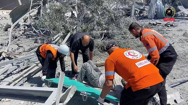 24일(현지시간) 가자지구 남부 칸유니스에서 구조대원들이 이스라엘군 공습을 받은 사상자를 들것에 옮기려고 하고 있다. 로이터연합뉴스