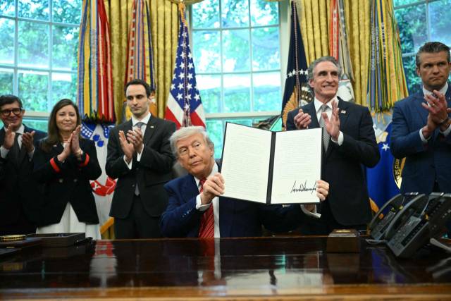 도널드 트럼프 미국 대통령이 23일(현지 시간) 백악관 집무실에서 원전 규제 완화와 관련한 행정명령에 서명한 후 들어 보이고 있다. AFP연합뉴스