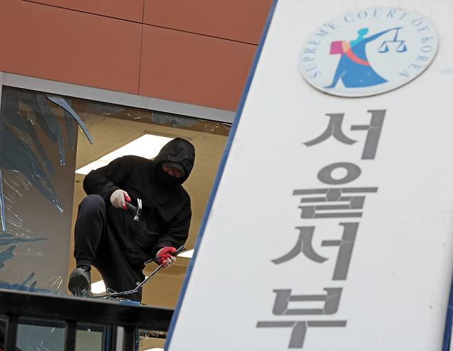 내란죄 피의자 윤석열 전 대통령의 구속 영장이 발부되자 윤 전 대통령의 지지자들이 서울 마포구 서울서부지법에 난입해 기물과 유리창 등을 파손한 뒤인 지난 1월19일 오후 건설업자가 깨진 창문의 유리를 제거하고 있다. 김영원 기자 forever@hani.co.kr