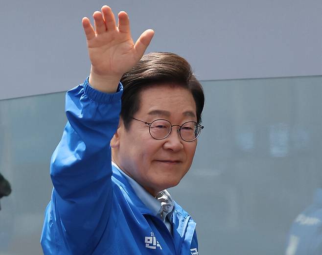 이재명 더불어민주당 대통령 후보가 26일 경기도 수원시 팔달문 영동시장 입구에서 유세를 마치고 퇴장하며 손을 들어 인사하고 있다. 공동취재사진