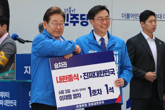 이재명 더불어민주당 대통령 후보가 19일 서울 용산구 용산역 광장에서 열린 집중유세에서 장경태 의원으로부터 이재명 열차 승차권을 받은 뒤 기념촬영을 하고 있다. 뉴스1