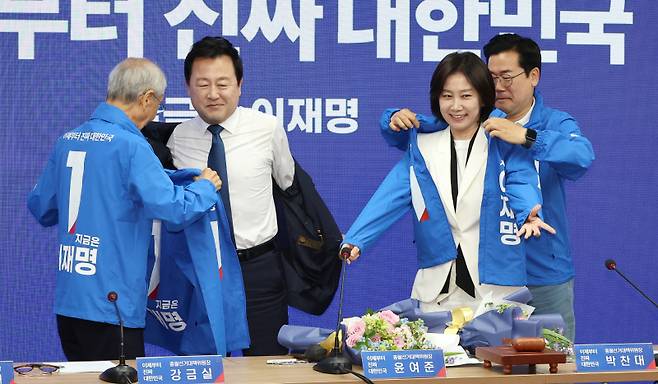 더불어민주당 박찬대 대표 직무대행 겸 원내대표(오른쪽)와 윤여준 총괄선대위원장(왼쪽)이 26일 서울 여의도 당사에서 열린 중앙선거대책위원회의에서 허은아(오른쪽 두번째), 김용남 전 의원에게 선거운동복을 입혀 주고 있다. 연합뉴스