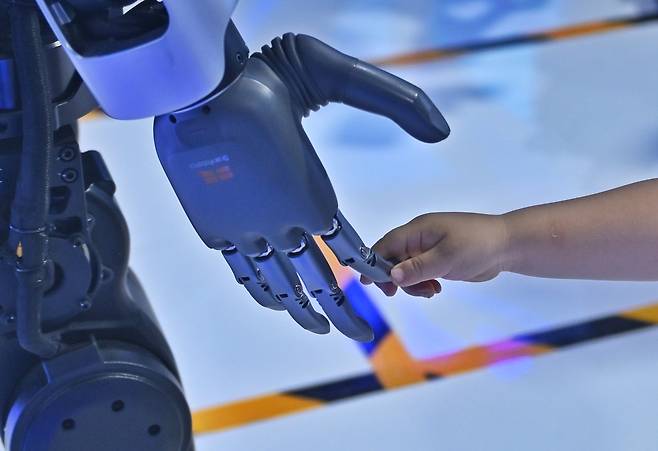 지난 25일 중국 남서부 쓰촨성 청두에서 열린 제20회 서중국 국제 박람회에서 한 어린이가 로봇과 상호작용하고 있다. [신화]