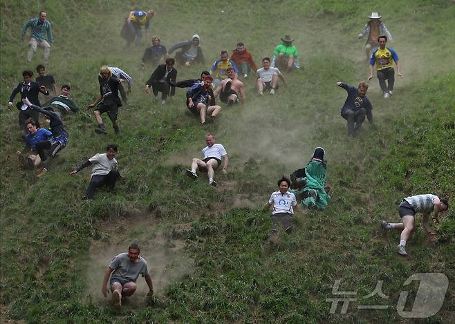 26일(현지시간) 영국 브록웍스의 쿠퍼스 힐에서 열린 '구르는 치즈 잡기' 대회에서 참가자들이 치즈를 쫒아 언덕을 내려가고 있다. ⓒ 로이터=뉴스1