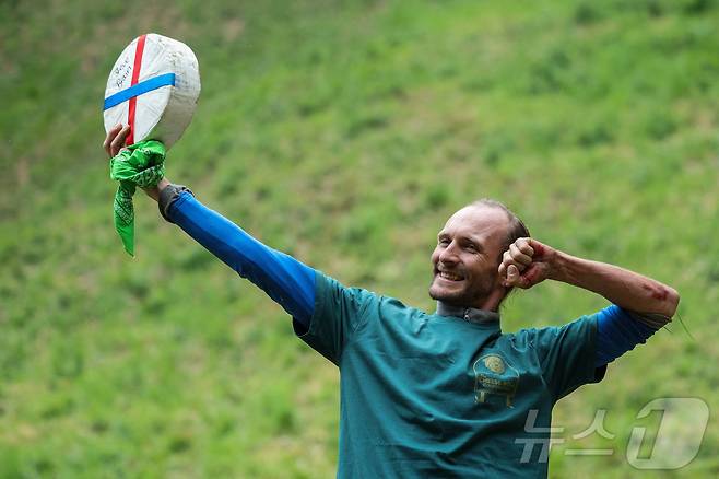 26일(현지시간) 영국 브록웍스의 쿠퍼스 힐에서 열린 '구르는 치즈 잡기' 대회 두 번째 경기에서 우승한 루크 브릭스가 치즈 바퀴를 들고 포즈를 취하고 있다. ⓒ 로이터=뉴스1