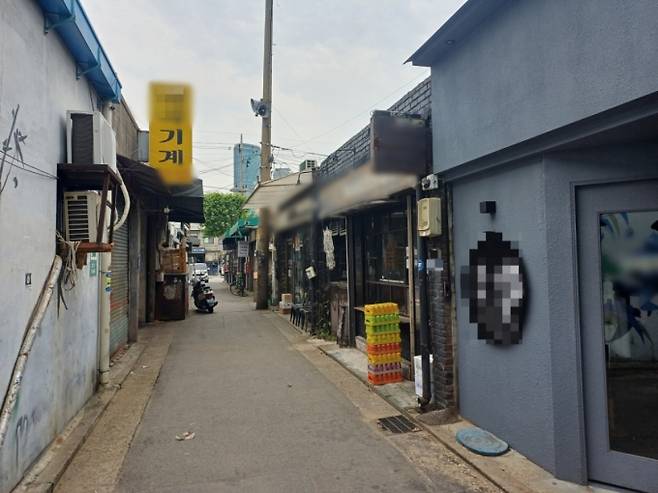 지난 25일 오전 서울 영등포구 문래동 골목에 문을 열지 않은 철공소가 있다. 맞은편에 술집과 카페가 늘어선 모습. /사진=오석진 기자.