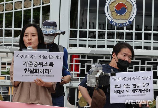 [서울=뉴시스] 김명원 기자 = 기초법바로세우기 공동행동 등 참석자들이 지난해 7월 25일 오전 서울 종로구 정부서울청사 앞에서 정부 중앙생활보장위원회에 기준중위소득 현실화와 부양의무자기준 완전 폐지를 요구하는 민중생활보장위원회 기자회견을 하고 있다. 2024.07.25. kmx1105@newsis.com