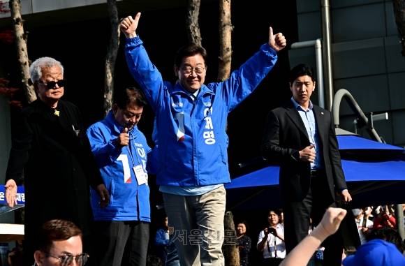 이재명 더불어민주당 대선 후보가 26일 경기 남양주시 평내호평역 광장에서 유세하며 두 손을 들어 지지자들에게 인사하고 있다. 왼쪽부터 배우 명계남, 김병주 의원, 이 후보. 홍윤기 기자