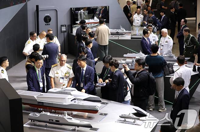 28일 부산 해운대구 벡스코 제1전시장에서 열린 '2025 국제해양방위산업전(MADEX)'에서 참가자들이 HD현대중공업 부스를 찾아 미래형 무인전력모함 등을 살펴보고 있다.  2025.5.28/뉴스1 ⓒ News1 윤일지 기자