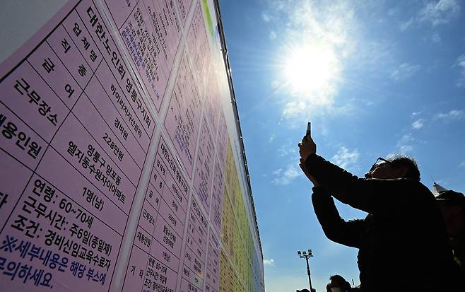 Elderly job seekers look at a hiring information board during a senior job fair at Hwaseong Haenggung Square in Paldal District, Suwon, on March 28, 2025./Yonhap