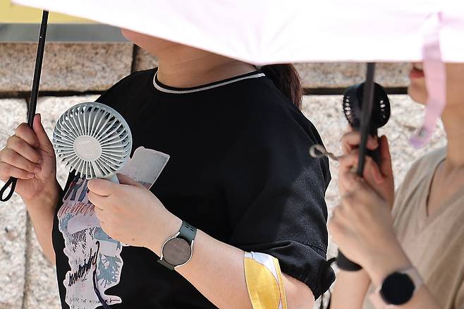 지난 26일 오후 서울 청계광장에서 시민들이 양산과 손 선풍기를 이용해 더위를 피하고 있다./뉴스1