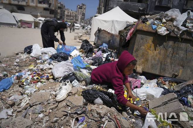 [가자시티=AP/뉴시스] 가자지구 내 팔레스타인 주민들의 절박함이 커지는 가운데 지난 25일(현지 시간) 다섯 자녀를 둔 40세 여성 이슬람 아부 타에마가 가자시티 쓰레기 더미 속에서 빵 한 조각을 줍고 있다. 2025.05.27.