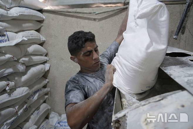 [데이르알발라=AP/뉴시스] 22일(현지 시간) 이스라엘이 일부 구호물자의 가자지구 반입을 허용함에 따라 세계식량계획(WFP)이 밀가루를 들여오자, 데이르알발라에서 팔레스타인 주민들이 빵을 굽고 있다. 2025.05.23.