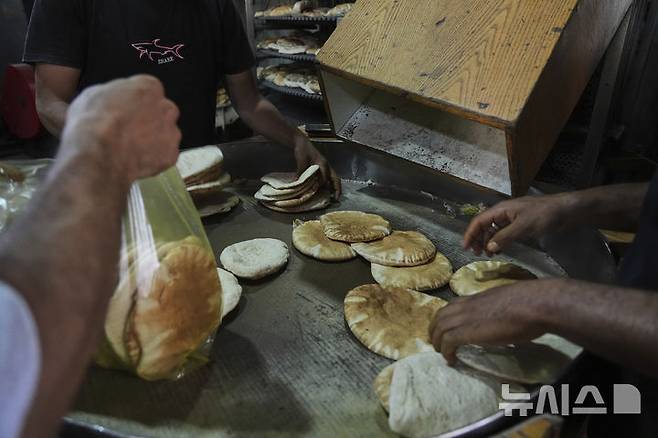 [데이르알발라=AP/뉴시스] 22일(현지 시간) 이스라엘이 일부 구호물자의 가자지구 반입을 허용함에 따라 세계식량계획(WFP)이 밀가루를 들여오자, 데이르알발라에서 팔레스타인 주민들이 빵을 굽고 있다. 2025.05.23.