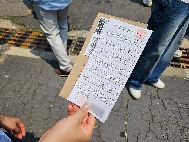 29일 오전 11시 25분쯤 구·신촌동주민센터 사전투표소에서 한 유권자가 배부받은 투표용지를 들고 투표소에 줄을 서 있다./매일경제 제공