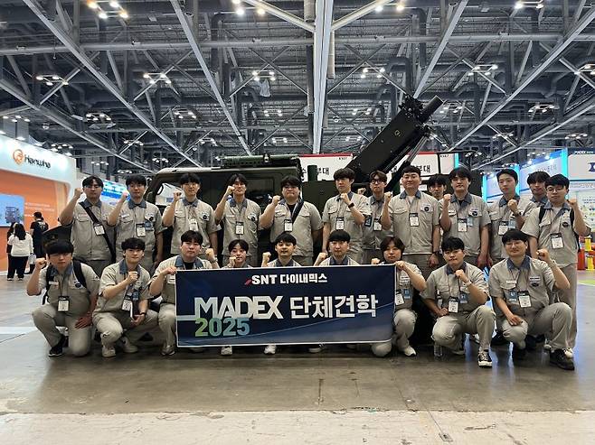 SNT다이내믹스 입차 3년차 미만 이공계 엔지니어들이 부산 벡스코에서 열리는 국제해양방위산업전 'MADEX 2025'에 단체견학 후 기념사진을 찍고 있다. SNT다이내믹스 제공