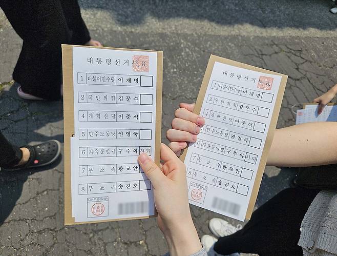 29일 오전 11시 25분쯤 구신촌동주민센터 사전투표소 밖에서 유권자들이 배부받은 투표용지를 들어 보이고 있다.  지혜진 기자