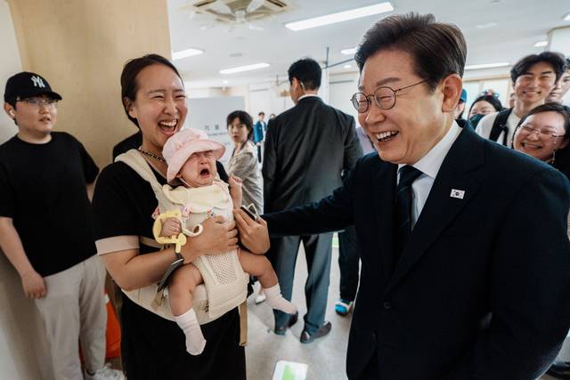 이재명 더불어민주당 대선 후보가 29일 서울 서대문구 신촌동 주민센터에서 제 21대 대통령선거 사전투표를 마치고 주민과 인사를 하던 중 안겨 있던 아이가 울음을 터뜨리자 멋쩍게 웃고 있다. 곽성호 기자