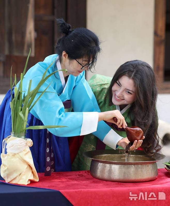 [서울=뉴시스] 김선웅 기자 = 단오(음력 5월 5일)를 이틀 앞둔 29일 서울 종로구 국립민속박물관 오촌댁 앞마당에서 열린 단오 세시행사에서 외국인 관광객이 창포물 머리감기 체험을 하고 있다. 2025.05.29. mangusta@newsis.com