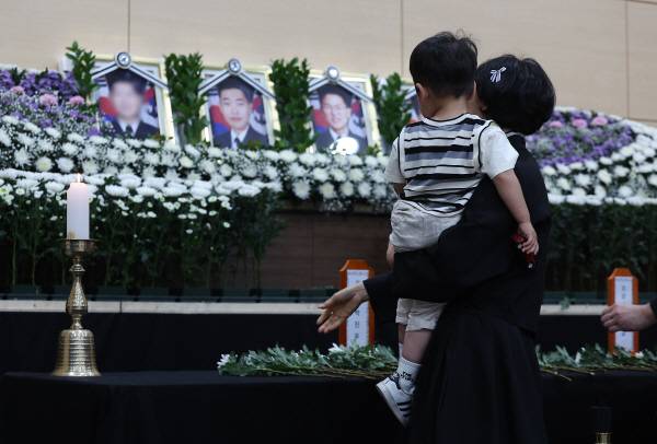 30일 경북 포항시 남구 해군 항공사령부 체육관에 마련된 '해군 P-3CK 917호기 순직자 합동분향소'에서 순직 해군의 유족과 어린 아들이 헌화하고 있다. 연합