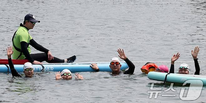오세훈 서울시장이 30일 오전 서울 송파구 잠실대교 남단에서 열린 제2회 쉬엄쉬엄 한강 3종 축제에 참여해 한강을 헤엄치다가 중간 쉼터인 모래톱 위에서 참가 시민들과 손을 흔들며 기념 촬영하고 있다. 2025.5.30/뉴스1 ⓒ News1 이동해 기자