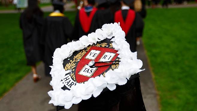 29일(현지 시각) 미국 매사추세츠주 케임브리지 하버드대학교에서  열린 제374회 졸업식 시작에 앞서 한 졸업생이 유학생들을 응원하는 의미로 하얀 꽃을 사각모에 꽂고 있다./EPA 연합뉴스
