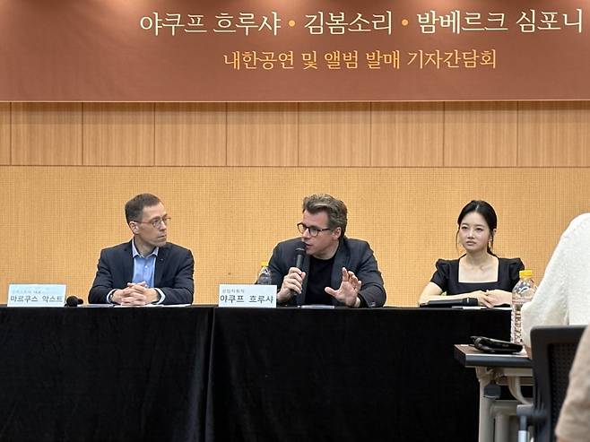 30일 서울 서초구 코스모스아트홀에서 열린 기자간담회에서 밤베르크 심포니 상임지휘자인 야쿠프 흐루샤(가운데)가 말하고 있다. 왼쪽은 마르쿠스 악스트 밤베르크 심포니 대표. 오른쪽은 바이올리니스트 김봄소리. / 사진 출처. 빈체로.