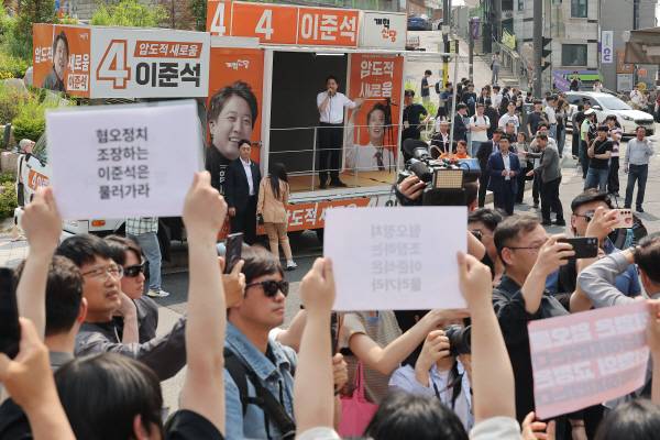 개혁신당 이준석 대선 후보가 30일 서울 동작구 중앙대학교에서 유세 중인 가운데 일부 학생들이 최근 이 후보의 TV토론 여성 신체 관련 발언을 규탄하며 팻말을 들고 있다. 연합뉴스