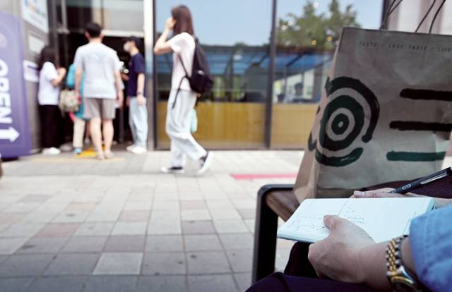 부정선거론 추종 단체인 ‘부정선거부패방지대’ 회원이 29일 서울의 한 사전투표소 출입구에서 투표 인원을 눈으로 직접 세며 노트에 기록하고 있다. 이한형 기자