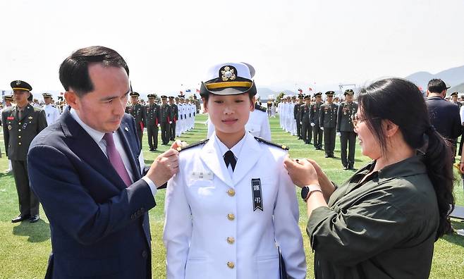 30일 경남 창원시 진해구 해군사관학교에서 열린 해군 사관후보생 수료 및 임관식에서 김해나 소위(가운데)가 최원일 전 천안함장(왼쪽)과 어머니에게 계급장을 수여받고 있다.  해군