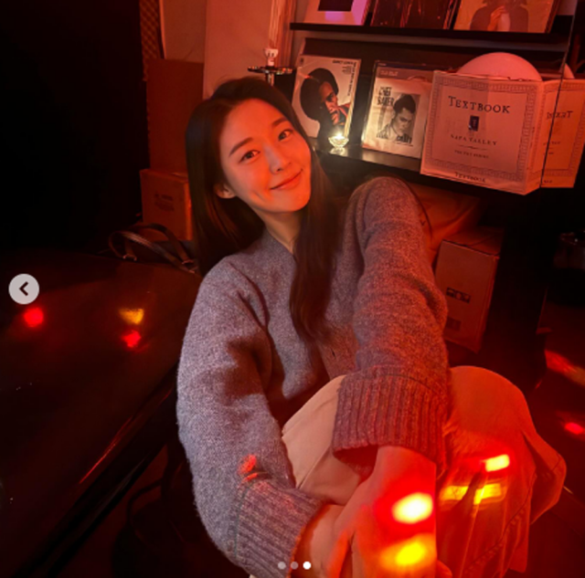 설현은 붉은 조명 아래 사랑스러운 미소를 짓고 있다./설현 인스타그램