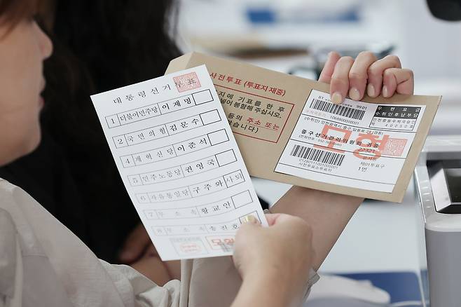 제21대 대통령선거 사전투표소에서 관계자가 투표용지와 관외 사전투표자를 위한 회송용 봉투를 들어보이고 있다. 연합뉴스
