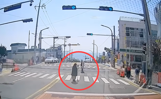 도로 한복판에서 기념사진을 촬영하던 커플이 자동차 주행 신호로 바뀌었는데도 자리를 비키지 않고 있다. 유튜브 한문철TV캡처