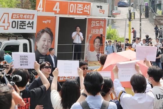 개혁신당 이준석 대선 후보가 30일 서울 동작구 중앙대학교에서 유세 중인 가운데 일부 학생들이 최근 이 후보의 TV토론 여성 신체 관련 발언을 규탄하며 팻말을 들고 있다. 연합뉴스